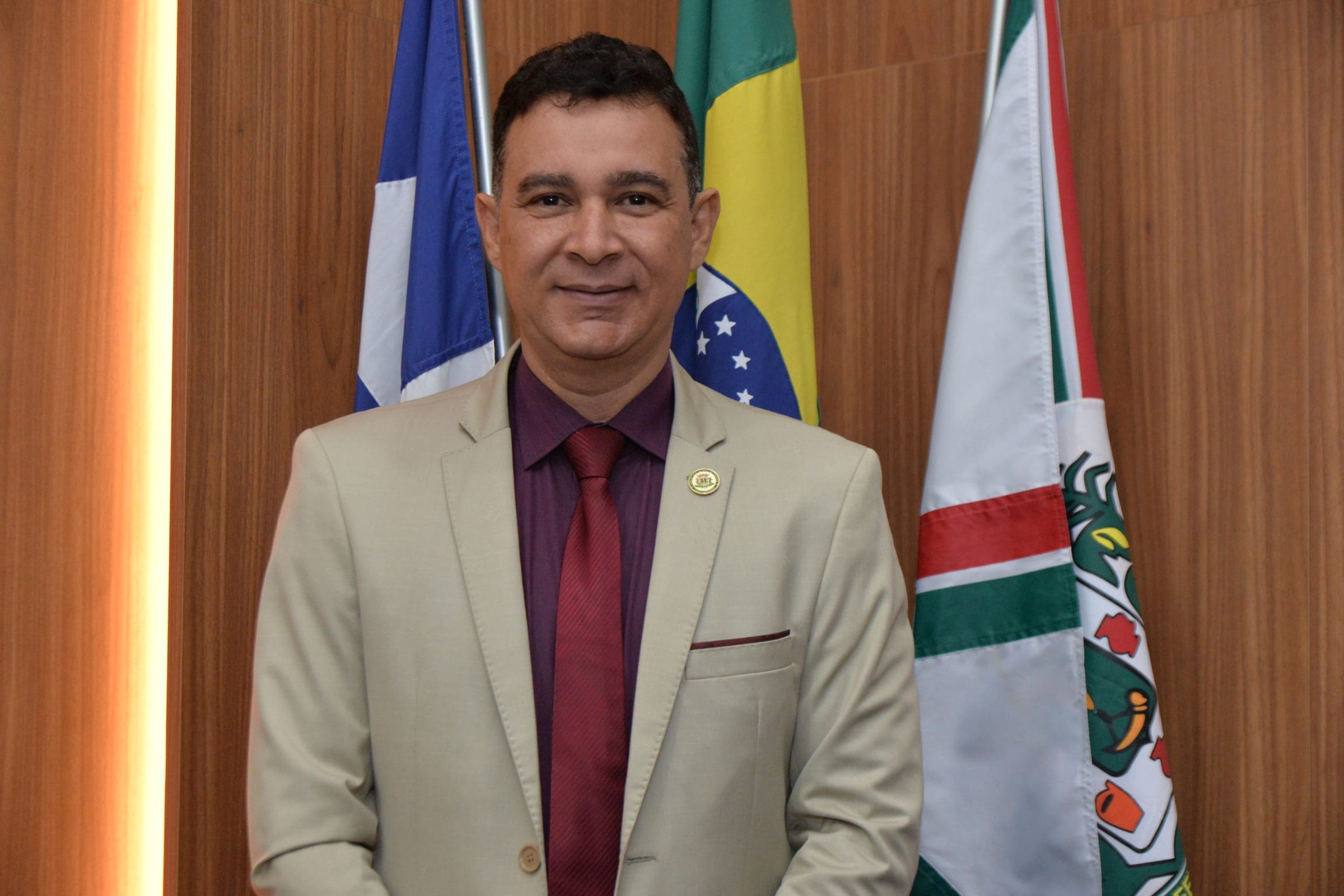 Marcos Lima diante das bandeiras do Brasil, da Bahia e de Feira de Santana.